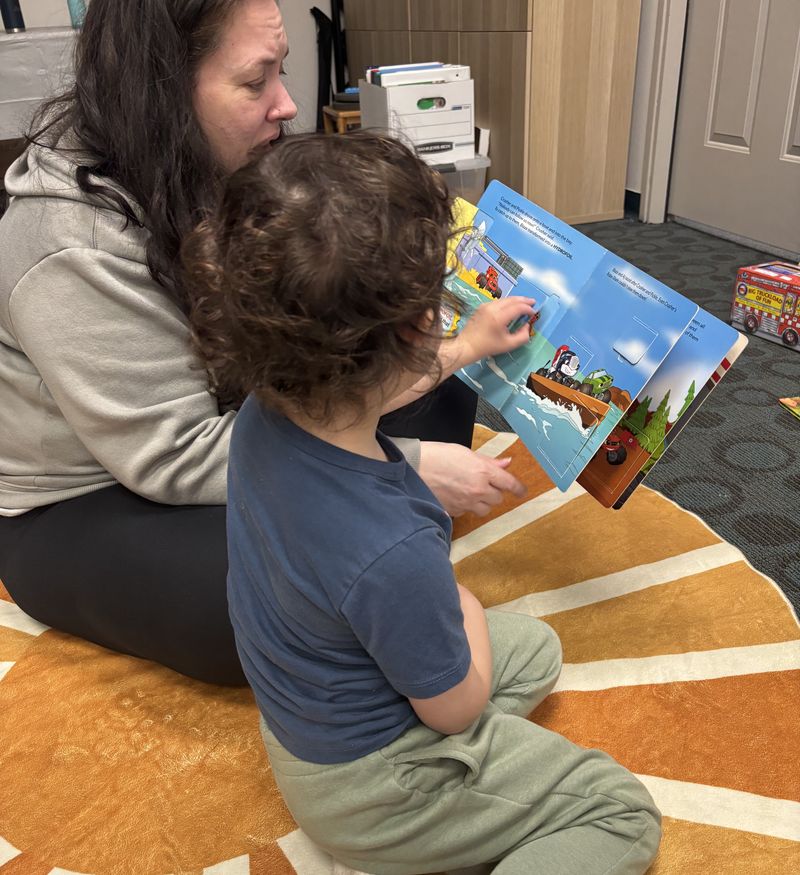 A therapist on the floor sharing a picture book with a child
